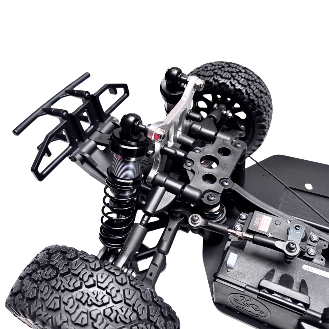 Close-up of a detailed model vehicle chassis with suspension and tires on a white background