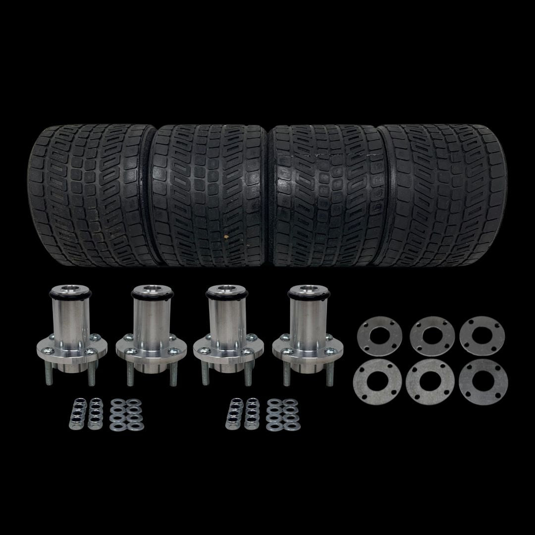 A set of four black street pattern tyres with metal billet wheel adaptors, studs, washers, plates, and nuts laid out in front.