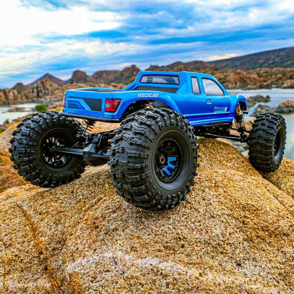 Blue remote-controlled truck on rocky terrain with a scenic background
