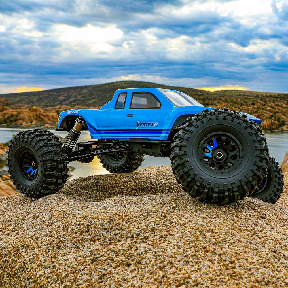 Blue off-road model truck on a rocky surface with a scenic background