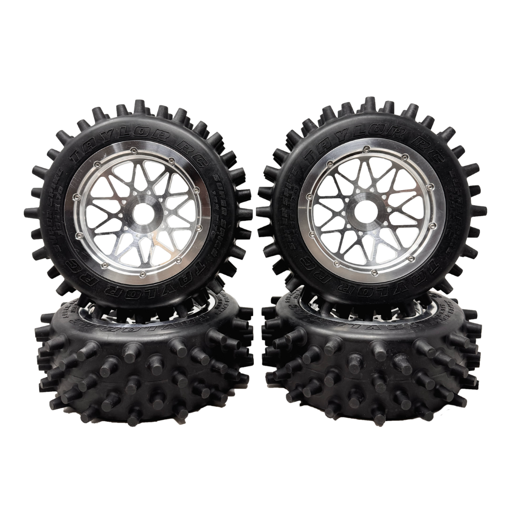 Four black off-road wheels with spiky tire treads on a white background