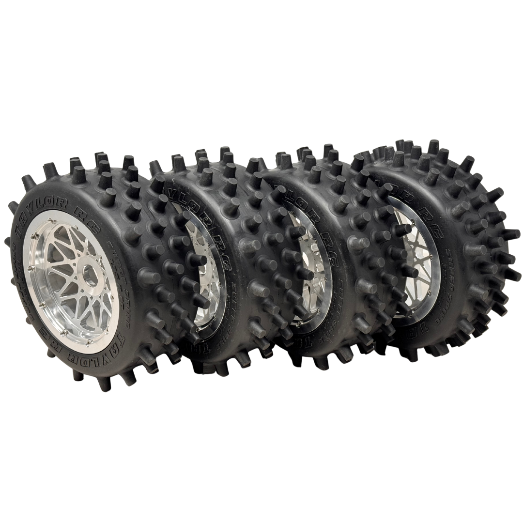 Four black off-road tires with spiky treads on a white background