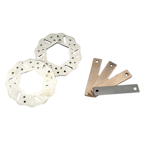 Two metallic brake rotors and four metal shims on a white background