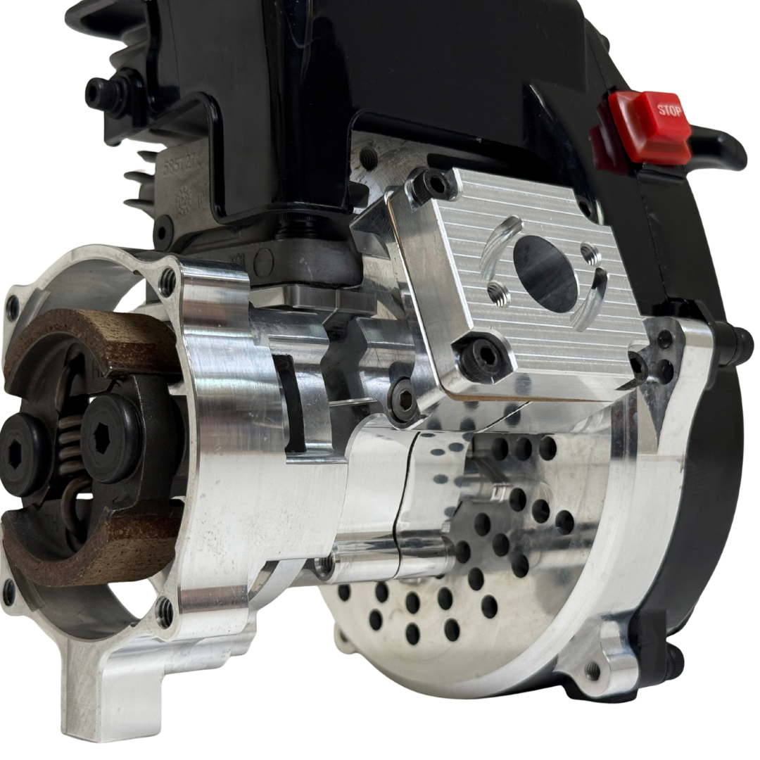 Close-up of the HPRC 34cc race ported Zenoah engine's raw silver billet bell housing, showing the clutch shoe, vented cooling holes and reed case mount
