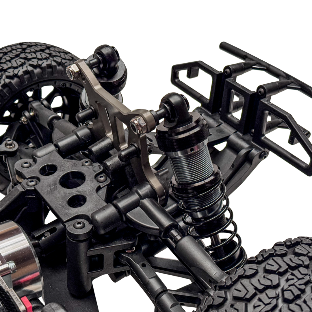 Close-up of a detailed model vehicle chassis with suspension and wheel setup on a white background