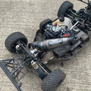 Close-up of a detailed RC car chassis with visible branding on a concrete surface