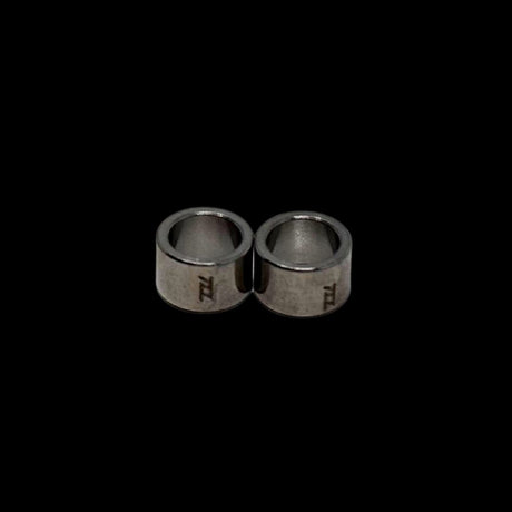 Pair of silver bushings with engraved tzz logo on a black background