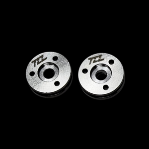 Two metal MCD shock pistons with TZZ logo on a black background