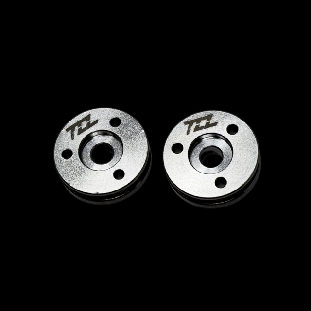 Two metal MCD shock pistons with TZZ logo on a black background